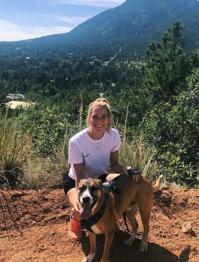 Erika smiling while on a hike with her dog