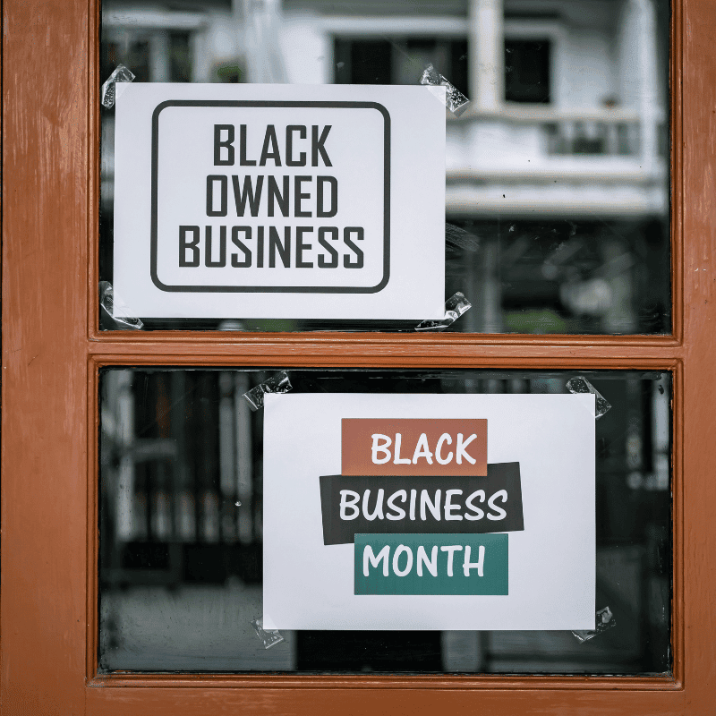 Storefront window with signs that say "Black Owned Business" and "Black Business Month"